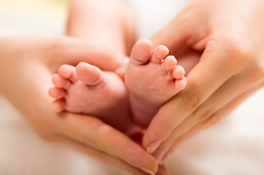 Manos de una mamá sosteniendo los pies de su bebé