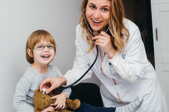 Médica revisando a un niño con su osito