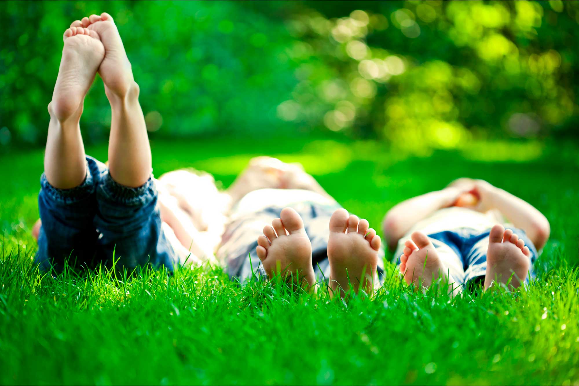 Niños descalzos acostados en el pasto, con los pies al aire