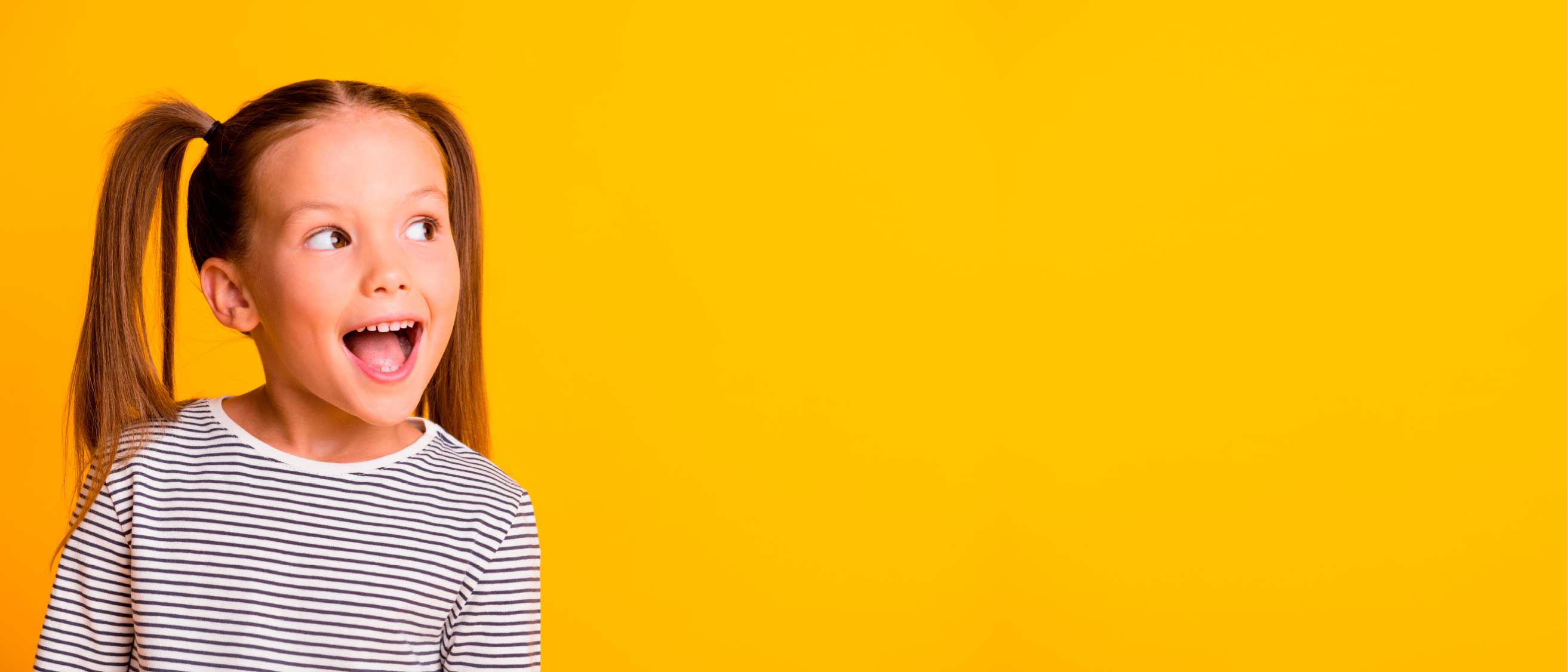Niña sonriente y sorprendida sobre fondo amarillo
